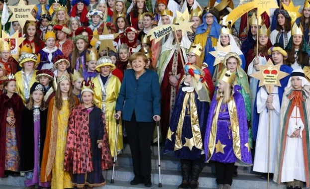 На патерици Меркел пя коледни песни със стотина деца