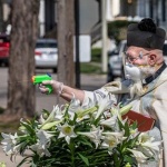 Свещеник пръска светена вода с воден пистолет, за да спази дистанцията